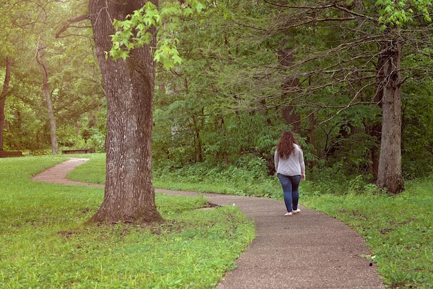 Foto vista posteriore di una giovane donna che cammina su un sentiero nella foresta
