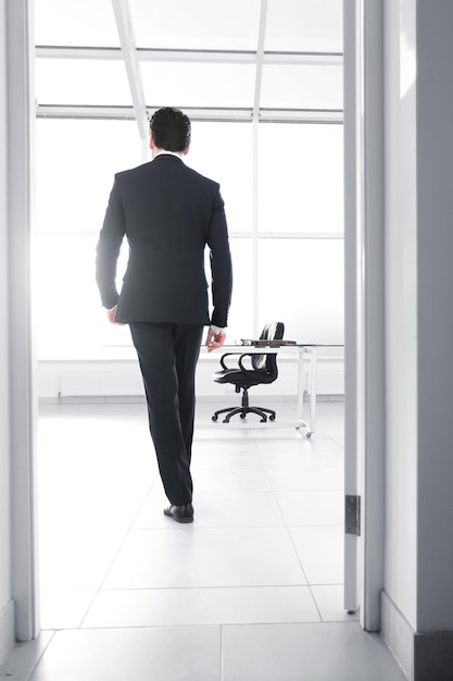 Rear viewbusinessman walks into his officebusiness concept