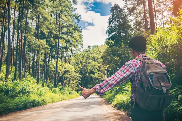 Rear of a young man with backpack goes on up to the mountain.