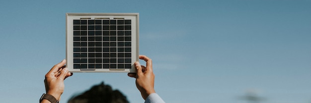 Rearview of eco-friendly woman holding a solar panel up in the sky