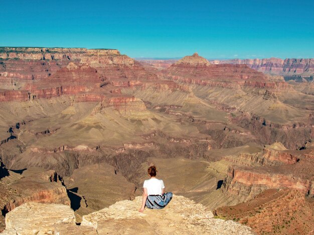 사진 그랜드 캐니언의 전망을 감상하는 바위 위에 앉아있는 여성의 리트 뷰