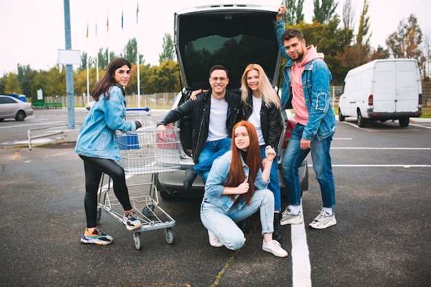 Rebel. Group of four young diverse friends in jeanse outfit look carefree, young and happy walking down the city's streets. Fashion of urban clothes, freedom, friendship, style concept.