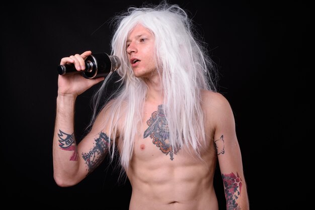 Rebelse man als punkrocker met pruik shirtless tegen zwart