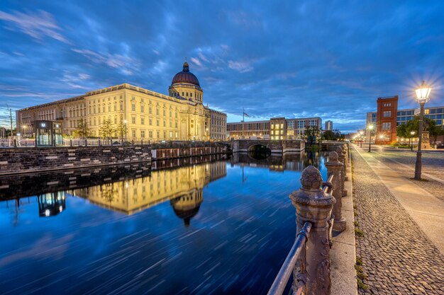 The rebuilt berlin city palace reflected in a small canal before sunrise