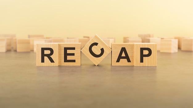 RECAP word text written on wooden cubes on a yelllow background