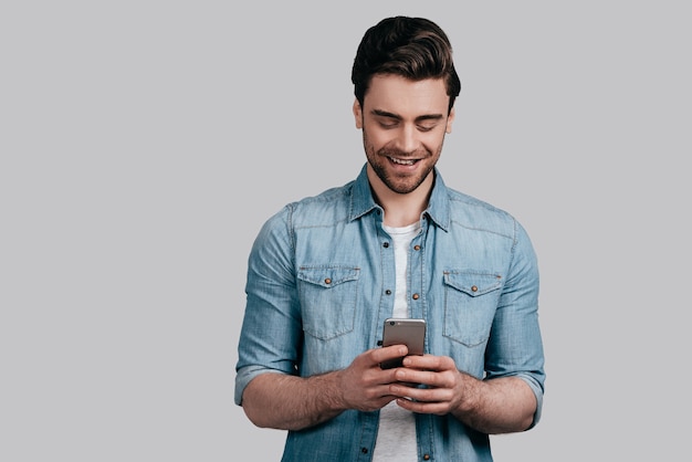 Receiving nice messages. Casual guy posing against the white wall