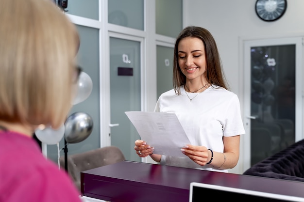 Receptie en hal in medisch centrum. Jonge gelukkige geduldige vrouw met diagnoselijst. Gelukkige emoties