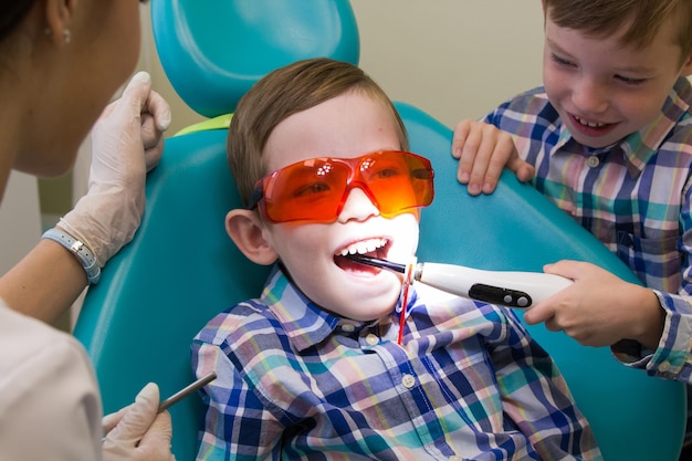 Reception at the dentistry a little boy lays on the couch and his brother puts the lamp in his mouth