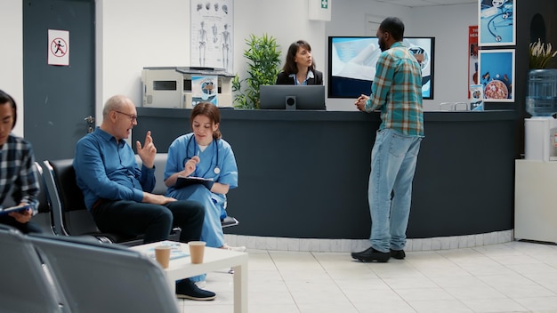 Reception desk with diverse patients waiting in lobby for\
checkup visit, people writing report at counter and mother with\
child in waiting area. appointments with physician and medical\
staff.