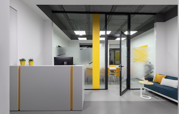 흰색 책상과 검은색 벽이 있는 노란색과 흰색 사무실의 리셉션 환영 공간