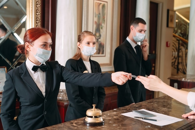 receptionist at counter in hotel wearing medical masks