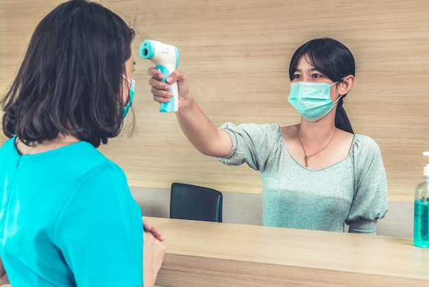 Receptionist and guest wearing face mask at front desk .