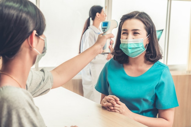 Receptionist and guest wearing face mask at front desk .