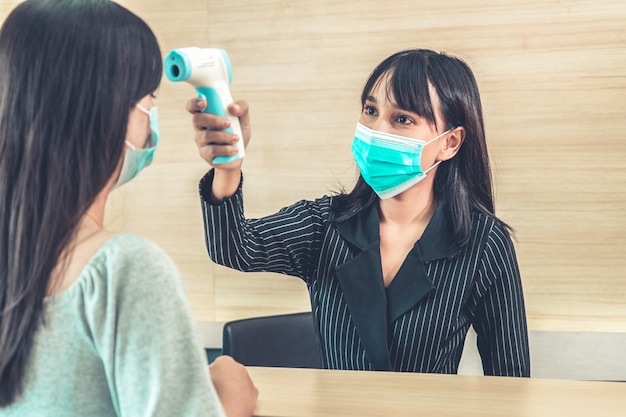 Receptionist and guest wearing face mask at front desk .