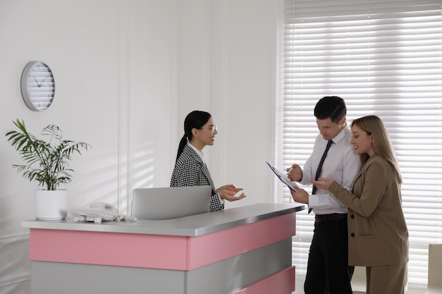 Receptionist working with clients at countertop in office