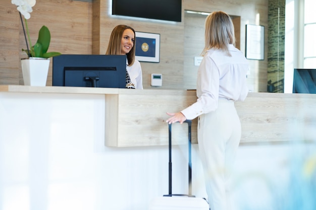 Foto receptioniste en zakenvrouw bij de receptie van het hotel