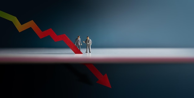 경기 침체 인플레이션 및 불황 개념 경제 위기 그래프 아래로 비즈니스 축소 빨간색 그래프 아래쪽 화살표를 보고 사업가의 두 개의 미니어처 그림