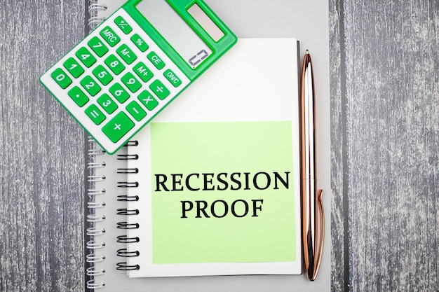 RECESSION PROOF text concept on a piece of paper next to a calculator Financial business concept recession proof