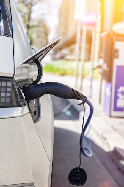 Photo recharging the battery of an electric car with green energy at charging station eco power portrait format cars