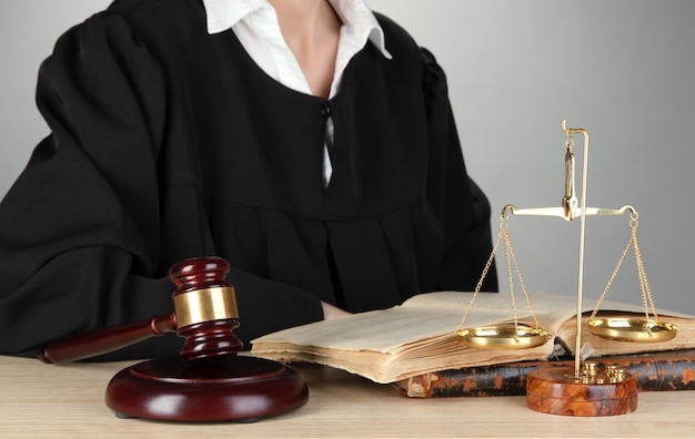 Rechter zittend aan tafel tijdens rechtszittingen op grijze achtergrond