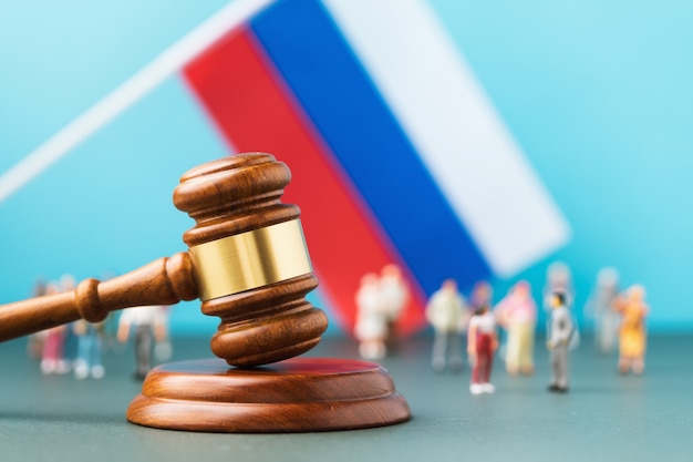 Rechterhamer, tegen de achtergrond van een vage vlag en plastic speelgoedmannetjes, het concept van rechtszaken in de Russische samenleving