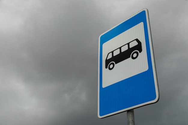 Foto rechthoekig blauw en wit bord van bushalte tegen sombere bewolkte hemel