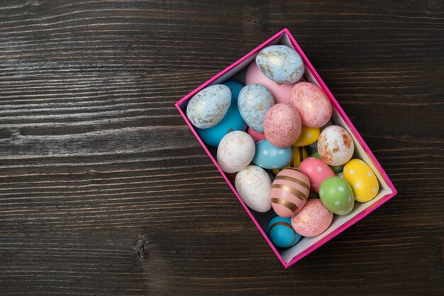 Rechthoekige doos met heldere veelkleurige paaseieren op hout