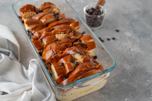 Ricetta per il budino di pane passo dopo passo pane con miscela di latte e gocce di cioccolato in una teglia