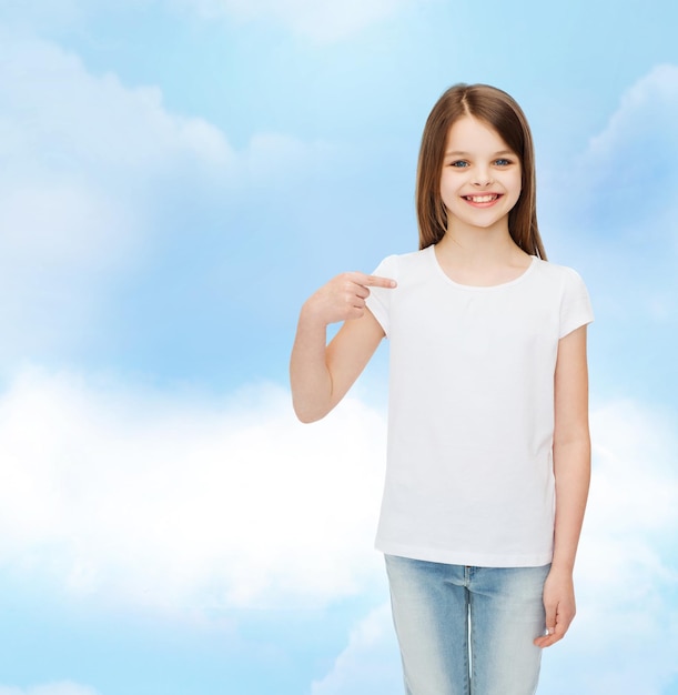 reclame, droom, jeugd, gebaar en mensen - glimlachend meisje in wit t-shirt wijzende vinger op zichzelf over bewolkte hemelachtergrond