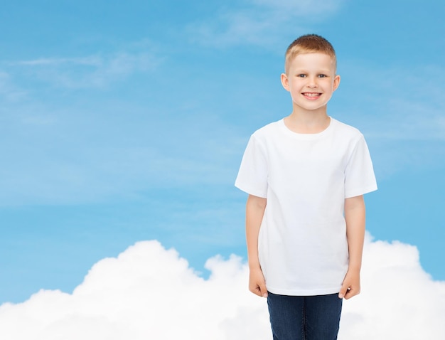 reclame, droom, mensen en jeugdconcept - glimlachende kleine jongen in wit leeg t-shirt over hemelachtergrond
