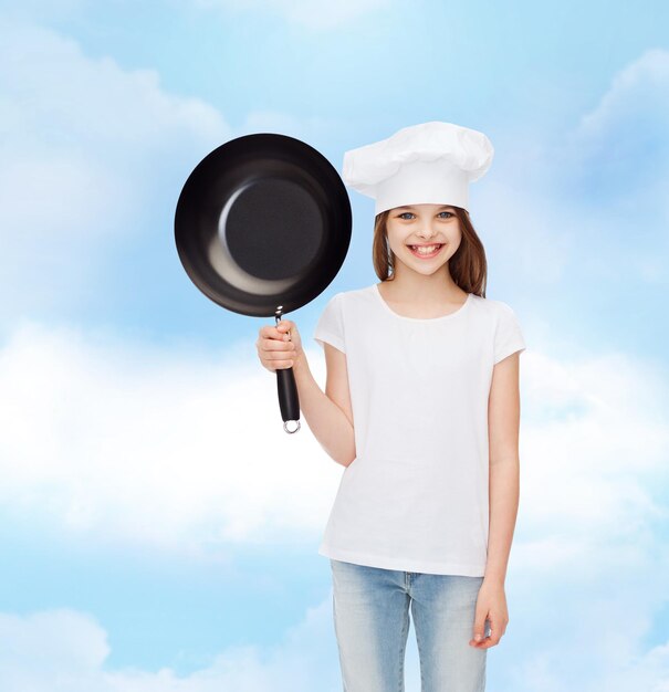 reclame, jeugd, koken en mensen - lachend meisje in wit t-shirt en kookhoed met pan over bewolkte hemelachtergrond