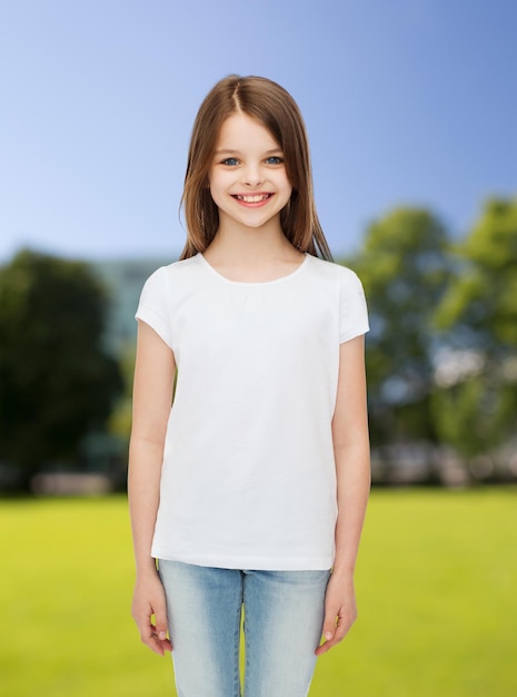 reclame, jeugd, natuur en mensen - glimlachend meisje in wit leeg t-shirt over groene parkachtergrond