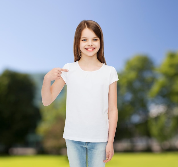 reclame, jeugd, natuur, gebaar en mensen - glimlachend meisje in wit t-shirt wijzende vinger op zichzelf over groene parkachtergrond
