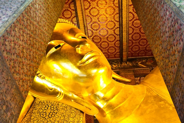 Volto statua di buddha in oro reclinabile. wat pho, bangkok, tailandia