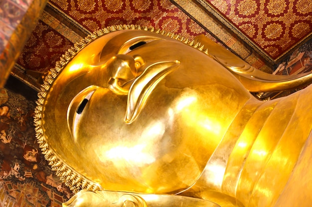 Statua adagiantesi dell'oro del buddha, wat pho, bangkok, tailandia.