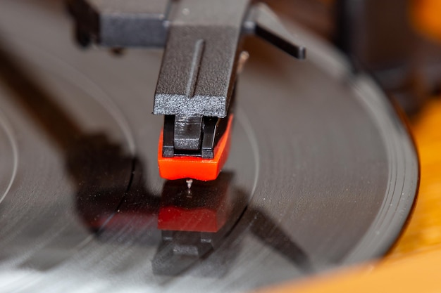 A record player with a red handle is on a wooden table.