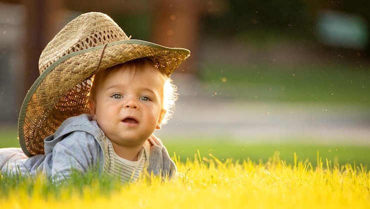 Recreation of children in the fresh air A little boy in a straw hat enjoys a warm summer day on the lawn near the cottage