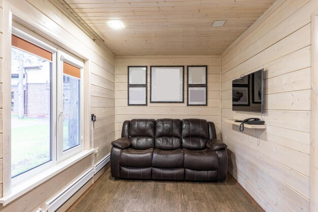 A recreation room with an expensive black leather sofa over which pictures hang a large tv in front