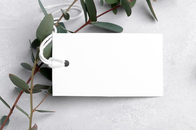 회색 배경 레이블 태그 모형 결혼식 호의 태그에 유칼립투스 잎이 있는 직사각형 흰색 선물 태그 모형