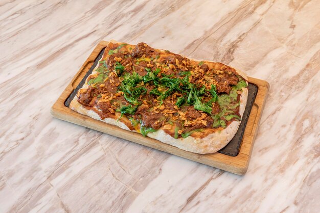 Rectangular barbecue pizza with shredded beef crispy onion and fried arugula