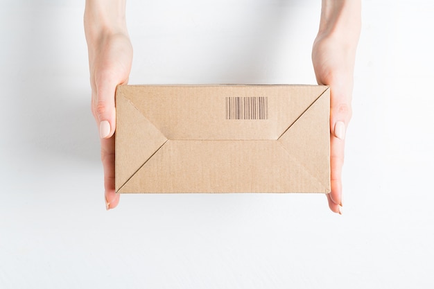 Photo rectangular cardboard box with barcode in female hands. top view,