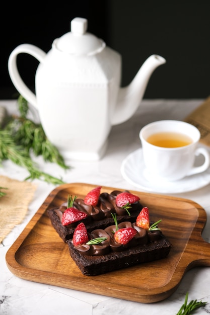 Photo rectangular chocolate tart with strawberry set in cafe table