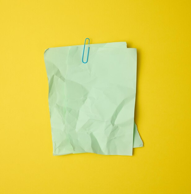 Photo rectangular crumpled blank green sheet of paper on yellow background