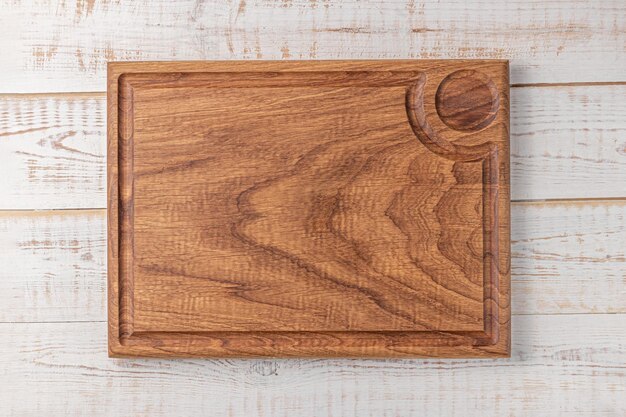 Rectangular cutting board with edging and place for a bowl of sauce on a white wooden table mockup of a food background with copy space top view