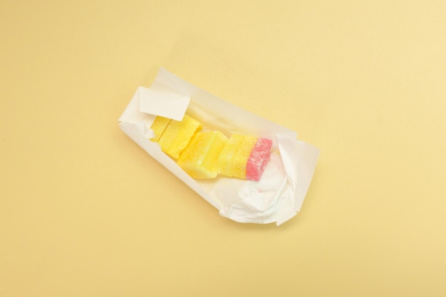 Rectangular multicolored sugar candies inside a white paper package on yellow background Dessert Fruit Tasty Colorful Taste Confection Eat Nobody Sugarplum Sweetie Sweety Colorful