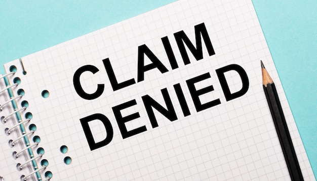 CLAIM DENIED 텍스트와 검은 색 연필이있는 직사각형 노트