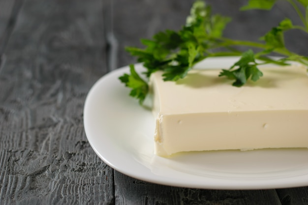 rectangular piece of Serbian cheese in a white bowl on a wooden table. view from the top. Dairy product. Flat lay.