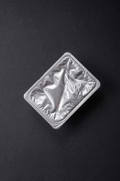 Прямоугольная пластиковая коробка с йогуртом или сыром, герметично закрытая крышкой из фольги.