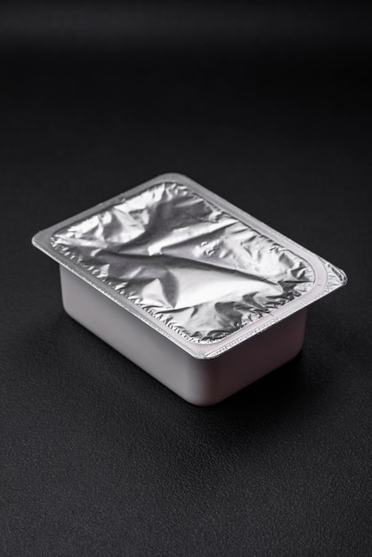 Photo rectangular plastic box with yogurt or cheese hermetically sealed with a foil lid