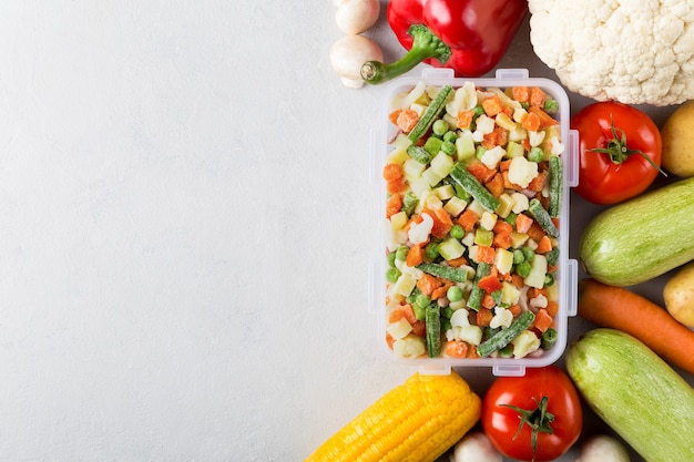 Rectangular plastic container with mix of frozen vegetables flat lay with copy space and fresh food